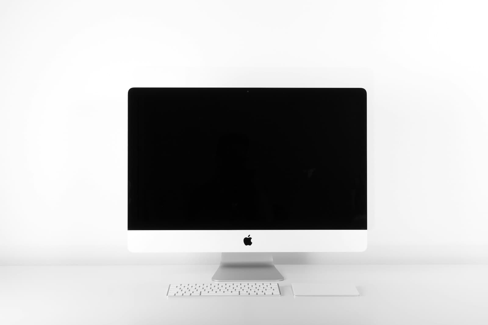 White all-in-one computer centered on a white desk with a slim keyboard